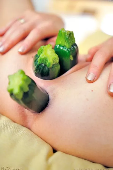 Молоденькая брюнетка засовывает здоровую порцию овощей в свою киску и жопу